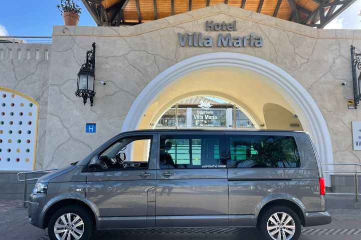 Gray van parked in front of Hotel Villa María entrance with arched doorway.