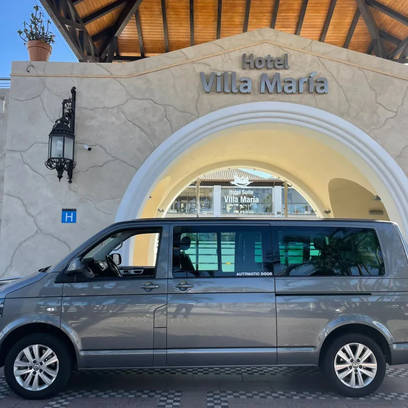 Gray van parked in front of Hotel Villa María entrance with arched doorway.