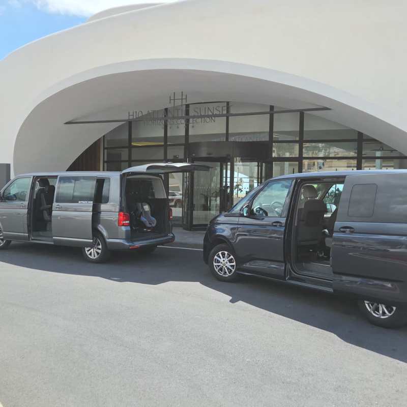 Two vans with open doors parked in front of a modern curved building.