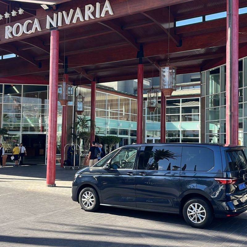 Hotel entrance with parked cars and large glass windows.
