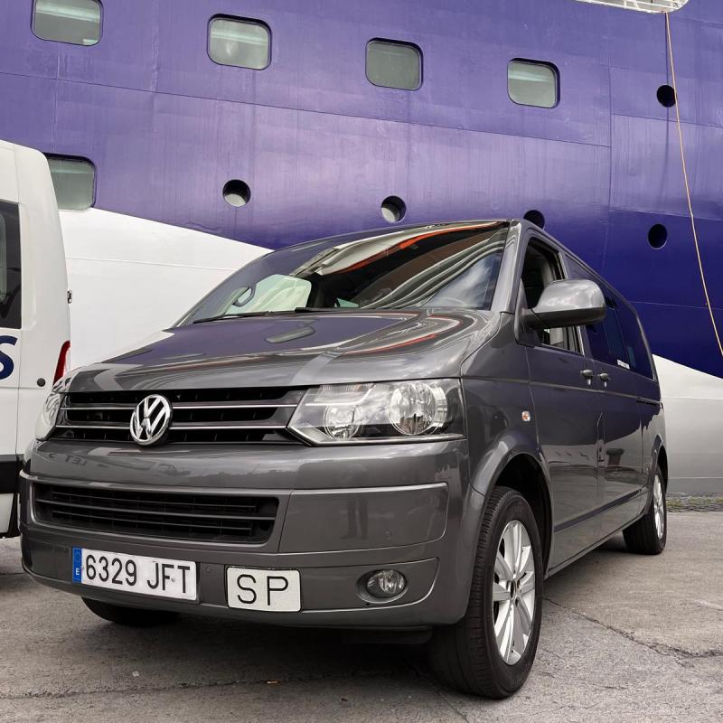 Gray Volkswagen van parked near a large blue and white ship.